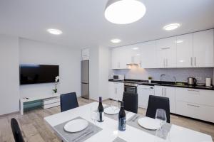 a kitchen with white cabinets and a table with wine bottles at Palm Mar de LUX A32 in Palm-Mar