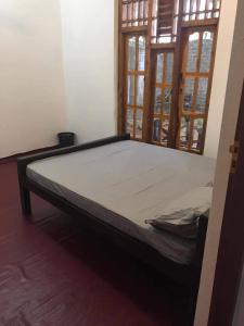 a bed in a room next to a window at Robbo's Surfcamp in Arugam Bay +6 photos