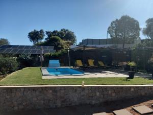 a swimming pool in a yard with a stone wall at Alagoas Park in Loulé