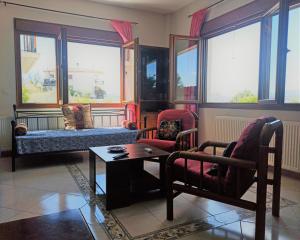 a living room with chairs and a table and windows at Casa di Rena in Nafplio
