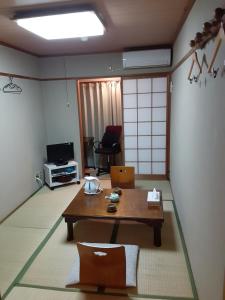 Zimmer mit einem Tisch und einem Wohnzimmer mit einem TV in der Unterkunft OHTO Ryokan in Kyoto