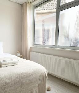 een slaapkamer met een bed en een groot raam bij Sea you soon in Den Burg