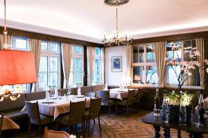 a dining room with tables and chairs and windows at Landhotel Bonsmann's Hof in Herdecke