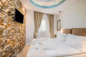 a bedroom with a white bed and a stone wall at Bella Terra Houses in Roda