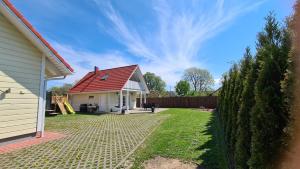 una casa con techo rojo y patio en Kasekese Holiday Home with Sauna and Garden, en Kuressaare