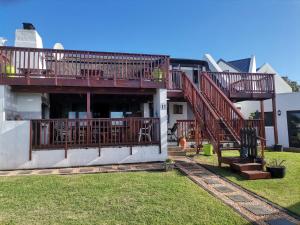 a house with a deck and stairs on it at Chilli Moon B&B in Stilbaai