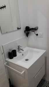een witte wastafel in een badkamer met een spiegel bij Duplex Bastié T3 calme et climatisé WiFi in Lyon +21 foto's