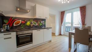 a kitchen with white cabinets and a counter with fruits and vegetables on the wall at Gästehaus Dobernig in Sankt Niklas an der Drau