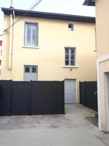 een huis met een zwart hek en twee garagedeuren bij Duplex Bastié T3 calme et climatisé WiFi in Lyon