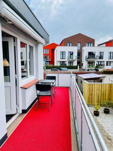 czerwony dywan na balkonie ze stołem i krzesłami w obiekcie Fischerbude w Büsum