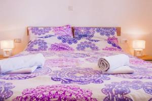 un letto viola e bianco con asciugamani di Fully renovated one bedroom apartment with a terrace - C a Sevid