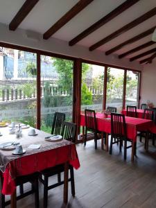 uma sala de jantar com mesas e cadeiras vermelhas e janelas em Risto's Guest House em Ohrid