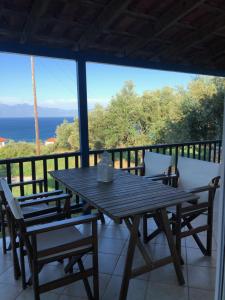 a wooden table and chairs on a balcony with a view of the ocean at Aggeliki House 5 in Kómboi