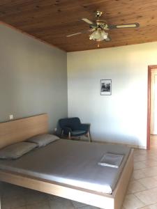 a bedroom with a bed with a ceiling fan and a chair at Aggeliki House 5 in Kómboi