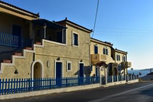een gebouw met een blauw hek naast een straat bij 3 Alpha Studios in Batsi