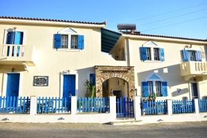 een huis met blauwe deuren en een hek bij 3 Alpha Studios in Batsi