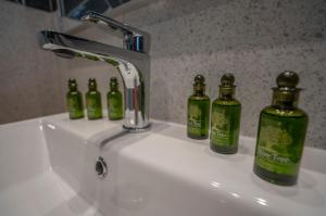 a bathroom sink with four green bottles on it at Tompazi 2 in Kavala +35 photos