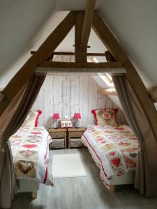 a attic bedroom with two beds in a attic at Les gîtes de "La Quesnoyère" in Quesnoy-le-Montant