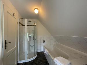 ein weißes Bad mit einer Dusche und einer Badewanne in der Unterkunft Gästehaus Zum Krug in Husum