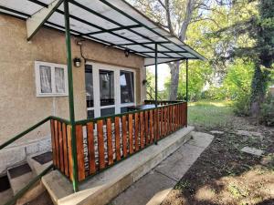Önálló nyaraló Balatonszárszón في بالاتونسزارسكو: شرفة منزل مع شرفة خشبية