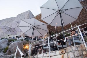 un gruppo di persone sedute sotto ombrelli bianchi di Room PlaceForYou a Dubrovnik