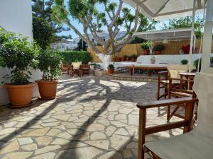 un patio con mesas, sillas y un árbol en Stefanos Katsaros Studios, en Skala