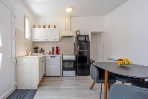 a kitchen with white appliances and a table with chairs at ORCHIDEE-7min aéroport Paris Orly-Arrivée autonome-Wifi et parking gratuit in Orly