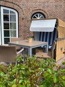un patio con parrilla, mesa y sillas en Ferienhaus Honigklee im Lüüvhoog en Keitum