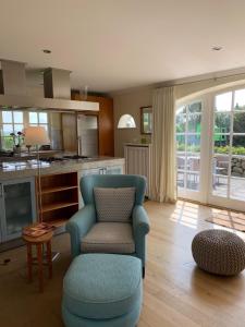 a living room with a blue chair and a kitchen at Ferienhaus Honigklee im Lüüvhoog in Keitum