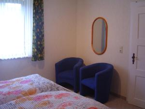 a bedroom with two blue chairs and a mirror at Ferienhaus Fam. Gottbehüt in Oberweid