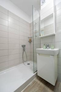 La salle de bains blanche est pourvue d'une douche et d'un lavabo. dans l'établissement Sunrise Studio - DeSilva Residence Mamaia Nord, à Mamaia