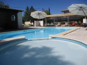a large swimming pool with umbrellas and chairs at Les Gîtes de l'Arbousier in Quissac