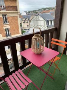 a pink table with chairs and a bird cage on a balcony at Duplex au cœur de Deauville avec vue imprenable et parking privé in Deauville