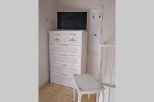 a white dresser with a tv and a chair at Serenity Cottage Feriolo in Baveno