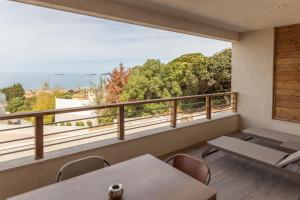 een kamer met een balkon met tafels en stoelen bij Résidence Kallisté Porticcio in Porticcio