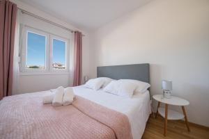 a bedroom with a bed with white sheets and a window at Romanca in Zadar