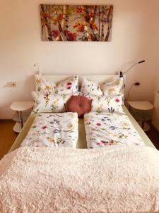 ein Bett mit weißer Bettwäsche und Kissen darauf in der Unterkunft Ferienwohnung Resi mit traumhaftem Seepanorama in Steindorf am Ossiacher See