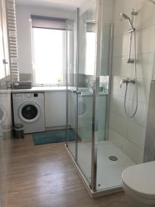 a bathroom with a shower and a washing machine at Beżowe Love in Olsztyn