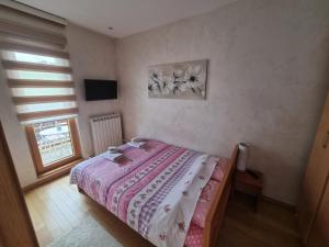 a small bedroom with a bed with a pink blanket at Apartman Dalija in Zlatibor