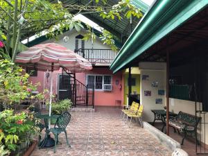 a patio with tables and chairs and an umbrella at Villa 301 B&B in Baclayon