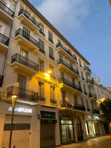 un gran edificio amarillo con balcones en una calle en Superbe 3 pièces refait à neuf classé 4 étoiles avec ascenseur et balcon à pied de la plage et du palais des festivals, en Cannes