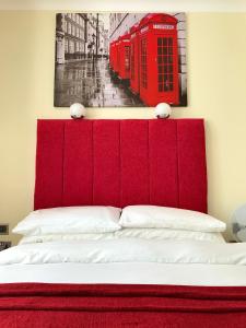 a bed with a red headboard and a picture of a phone booth at Cassandra Guest House in Plymouth
