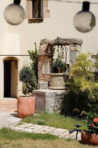 un jardin avec une fontaine en pierre et des plantes en pot dans l'établissement Masia del siglo XIV cerca de Barcelona, à Alella