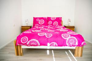 a pink bed with a pink and white bedspread at Oleander in Portorož