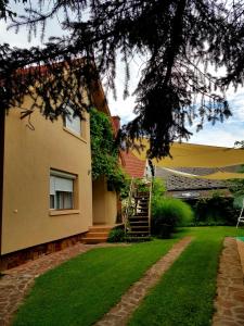 a house with a green lawn and a staircase at Borostyán Apartmann in Balatonföldvár