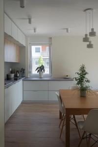uma cozinha com armários brancos, uma mesa e uma janela em Czartoryskiego 32 em Breslávia