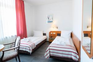a room with two beds and a table and a chair at Hotel Astoria am Urachplatz in Stuttgart