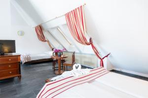 a bedroom with two beds and a tv and a table at Hotel Astoria am Urachplatz in Stuttgart