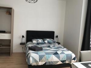 a bedroom with a bed with a blue and white comforter at Appartements du Vally - Guingamp in Guingamp