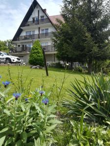 a house with a garden with flowers in front of it at Willa Tiramisu in Szczawnica